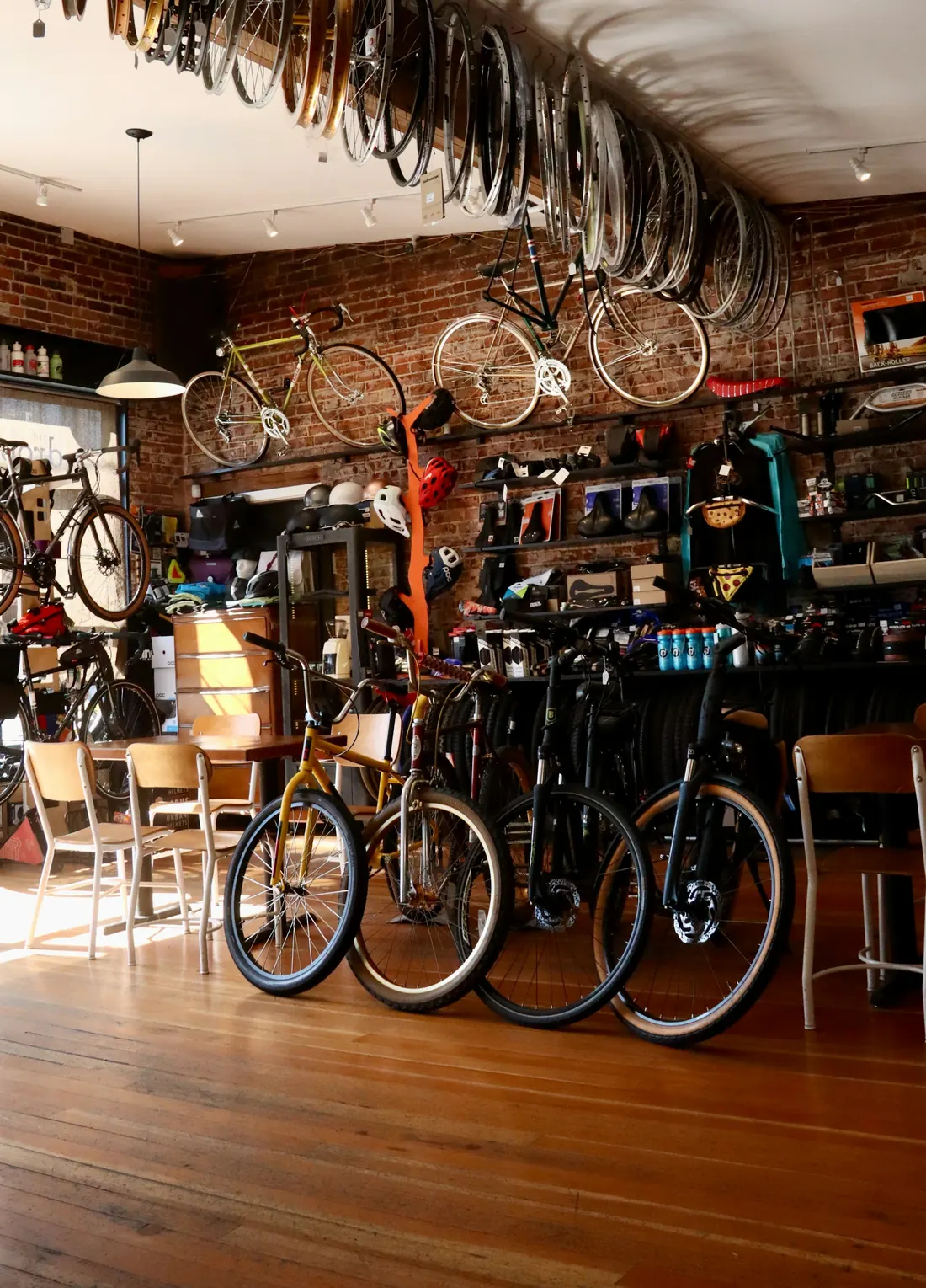 A row of bikes lined up inside a bike shop, with wheels hanging from the ceiling